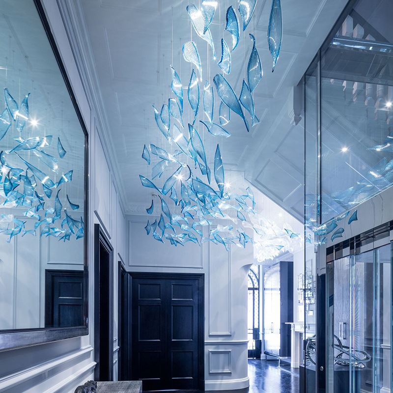 Long hallway or foyer with a large blue and white abstract glass art chandelier suspended overhead.